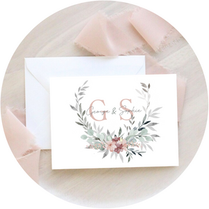 Close-up of a blush & grey wreath A6 Poppleberry accordion fold all-in-one wedding invitation, with a white envelope.