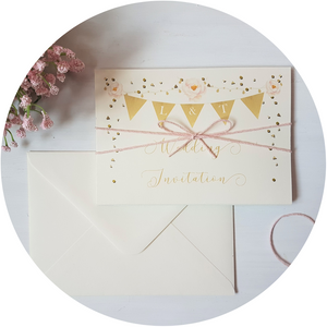 Golden bunting A6 Poppleberry accordion fold all-in-one wedding invitation, folded with blush pink twine & cream envelope.