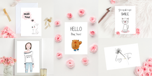 A showcase of 5 pieces of Poppleberry artwork, wedding invitations and positivity postcards with a warm "Hello" in the middle
