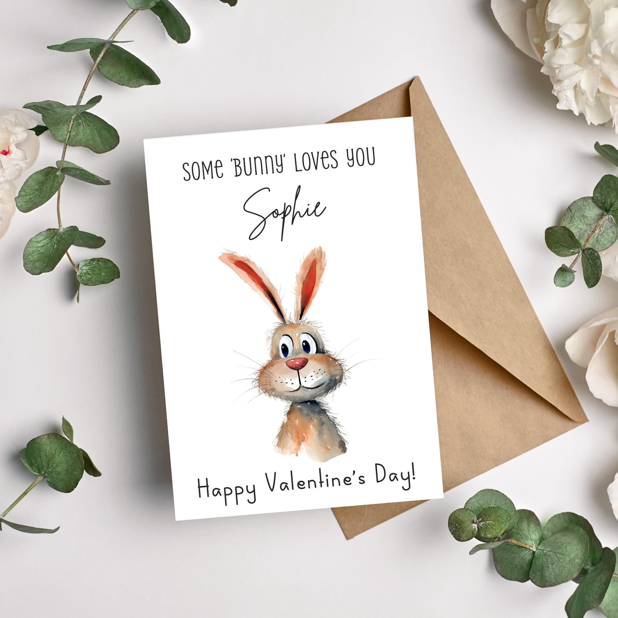 a valentine's day greeting card with a cute watercolour bunny rabbit in the centre of the card with the title above saying "some bunny loves you" followed by the first name of the recipient and underneath the rabbit the writing Happy Valentine's Day