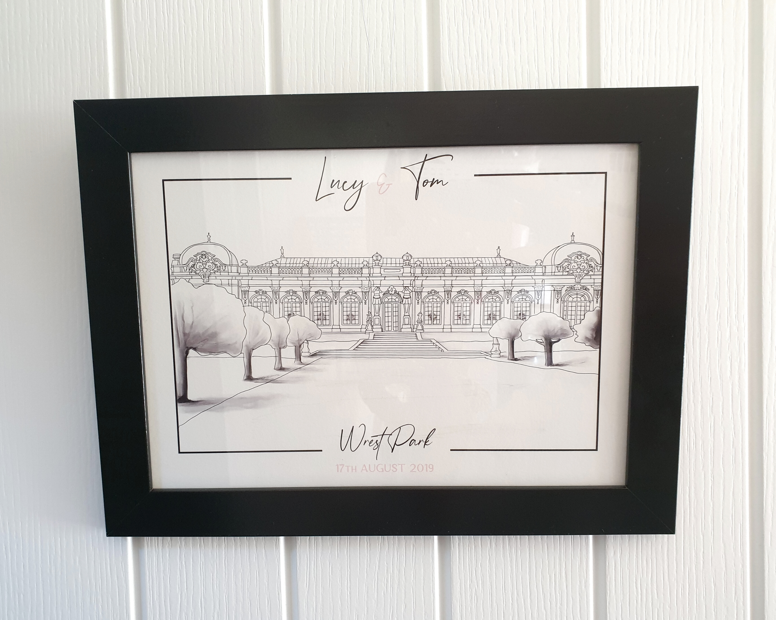 A digitally drawn wedding venue illustration of Wrest Park, with the couple's names at the top, in a black frame.