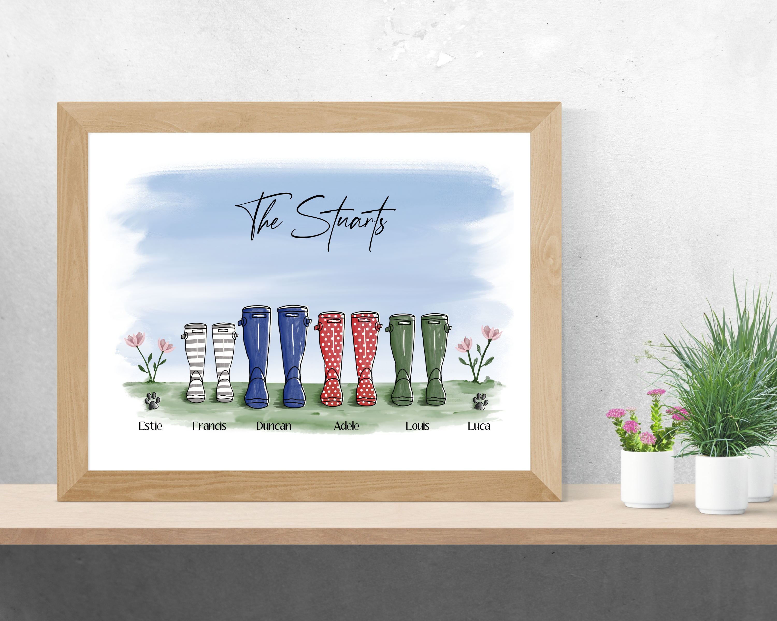 Poppleberry family of colourful wellington boots digital drawing art print, in a wooden frame on wall.