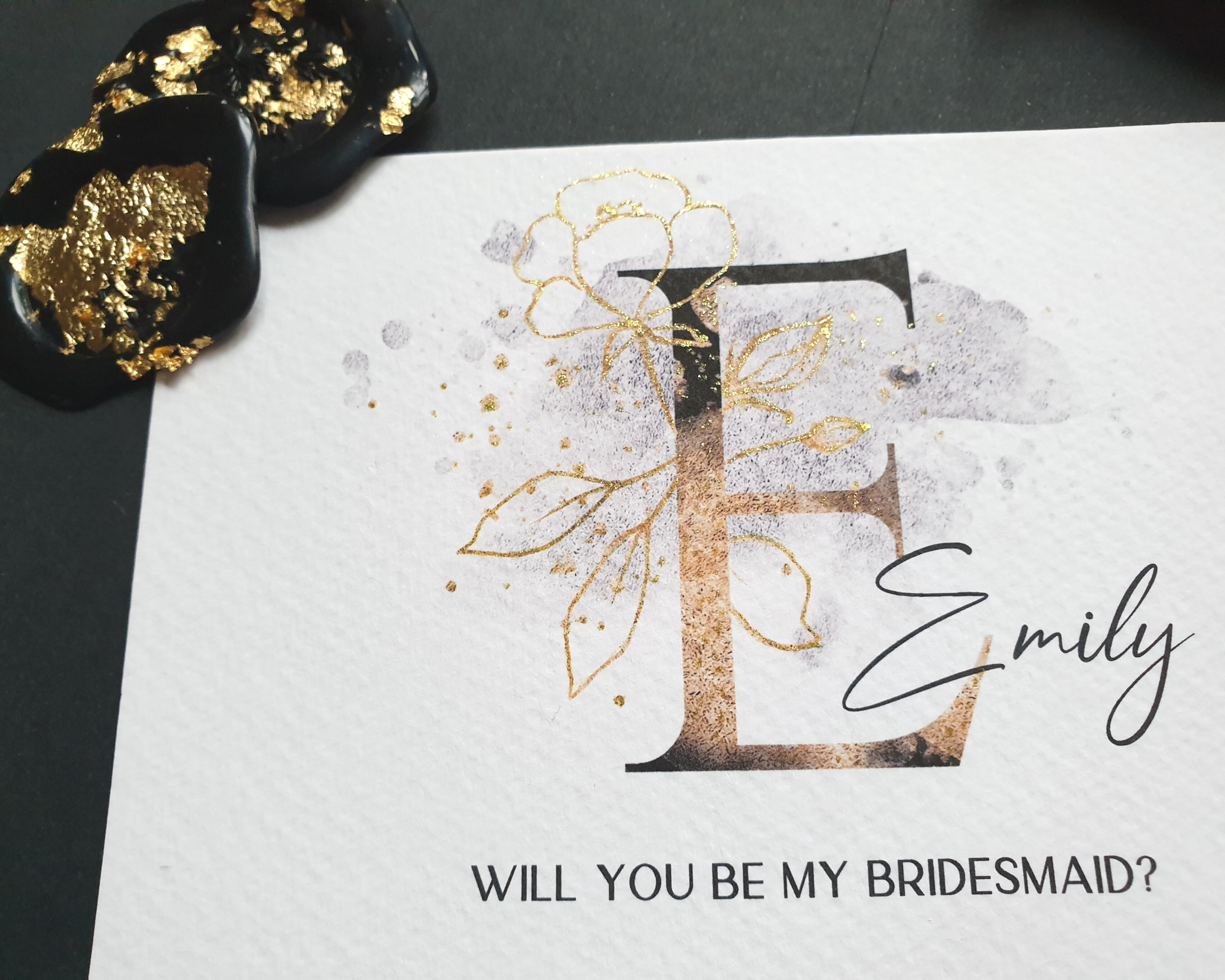 Close-up of a black & gold sparkle A6 Poppleberry 'Will you be my...?' bridesmaid proposal card with personalised name