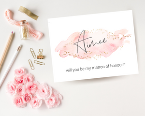 Close-up of a blush pink A6 Poppleberry 'Will you be my...?' bridesmaid proposal card with personalised name on white cardstock