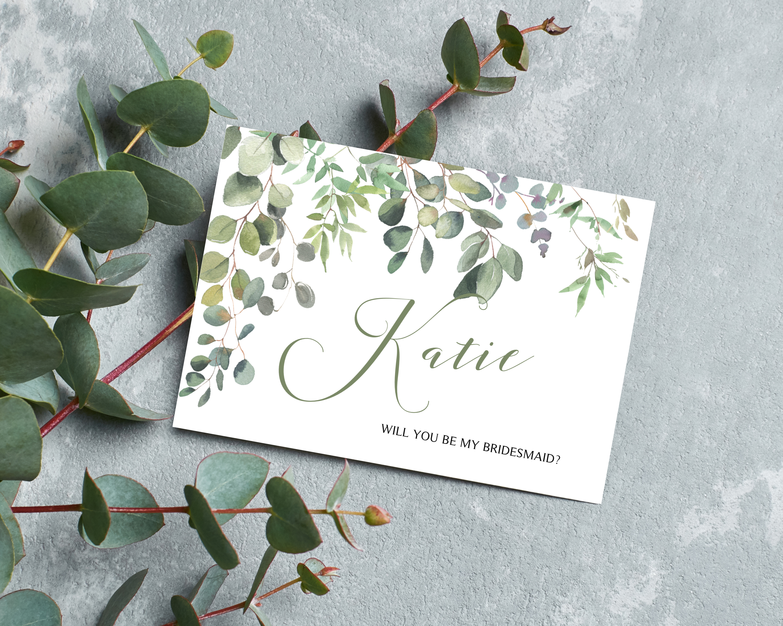 Front of a greenery & eucalyptus A6 Poppleberry 'Will you be my...?' bridesmaid proposal card with personalised name.