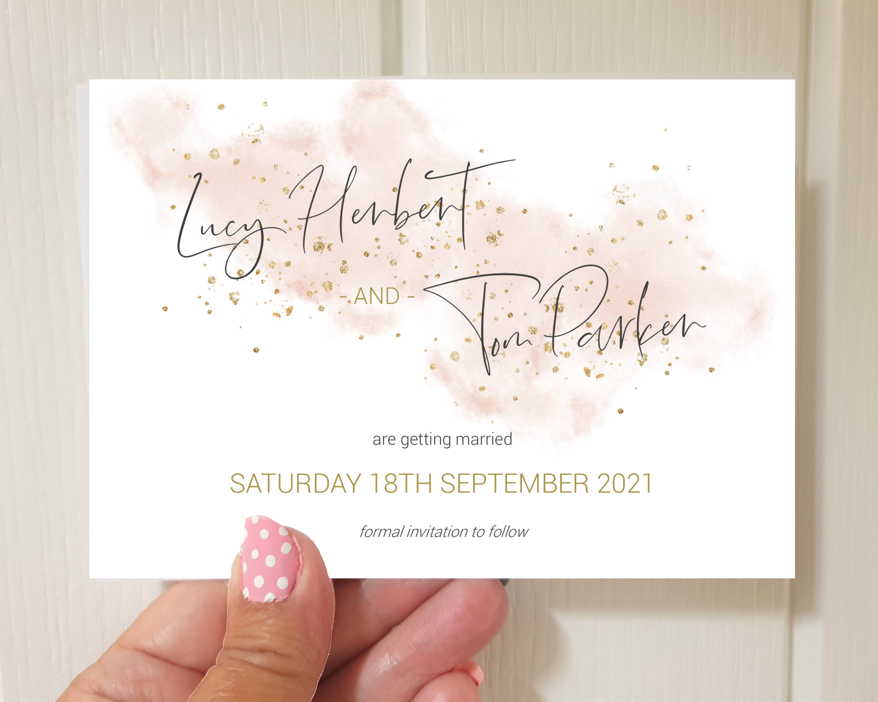A watercolour blush pink A6 Poppleberry one-sided wedding save the date card, with gold sparkles, held up.