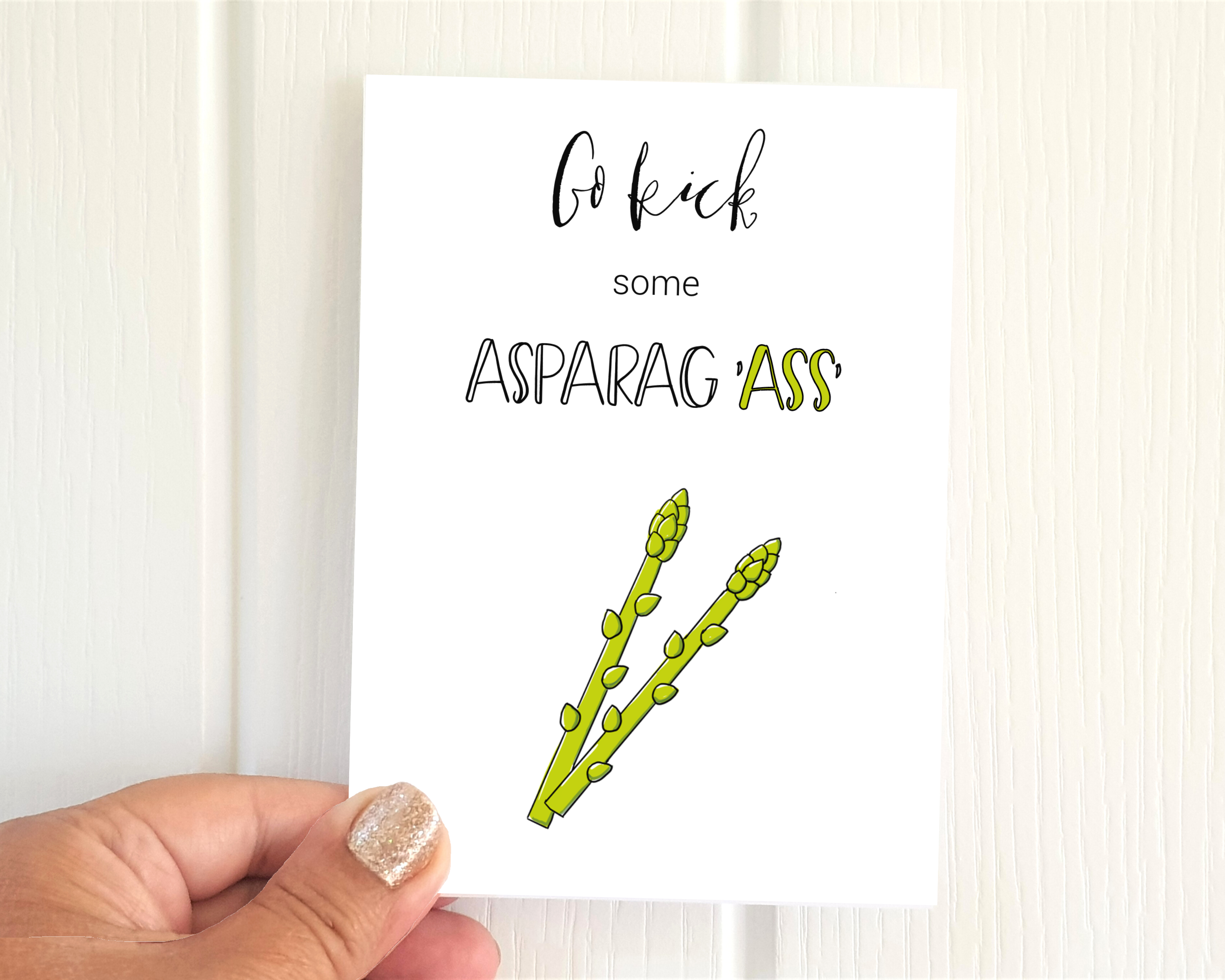 Poppleberry A6 'Kick some Asparag 'Ass'' positivity postcard, with an asparagus illustration & pun, on white cardstock.