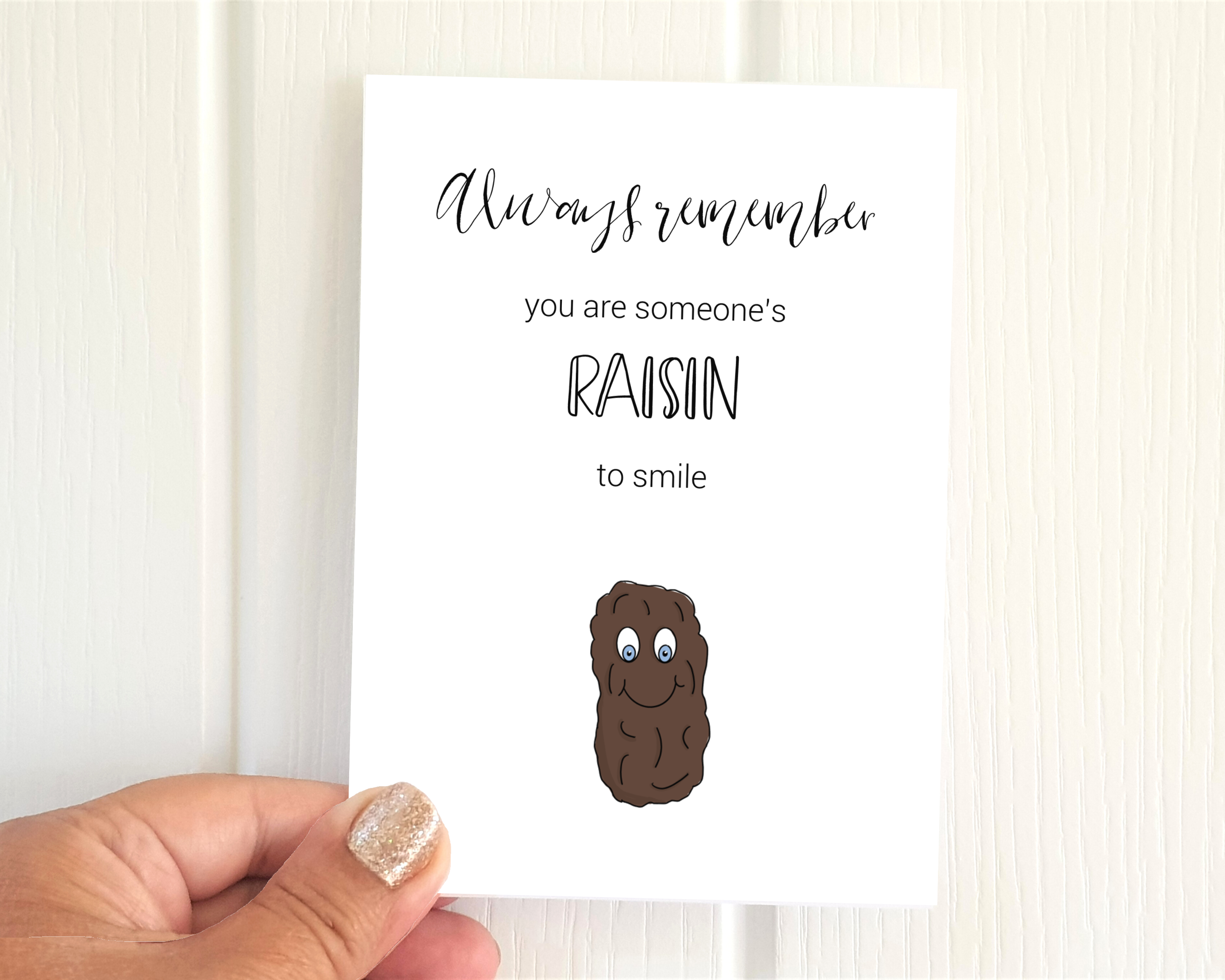 Poppleberry A6 'Someone's 'Raisin' to Smile' positivity postcard, with a raisin illustration & pun, on white cardstock.