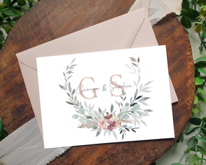 Close-up of a blush & grey wreath A6 Poppleberry accordion fold all-in-one wedding invitation, with a blush envelope.