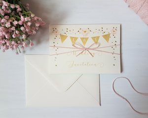 Golden bunting A6 Poppleberry accordion fold all-in-one wedding invitation, folded with blush pink twine & cream envelope.