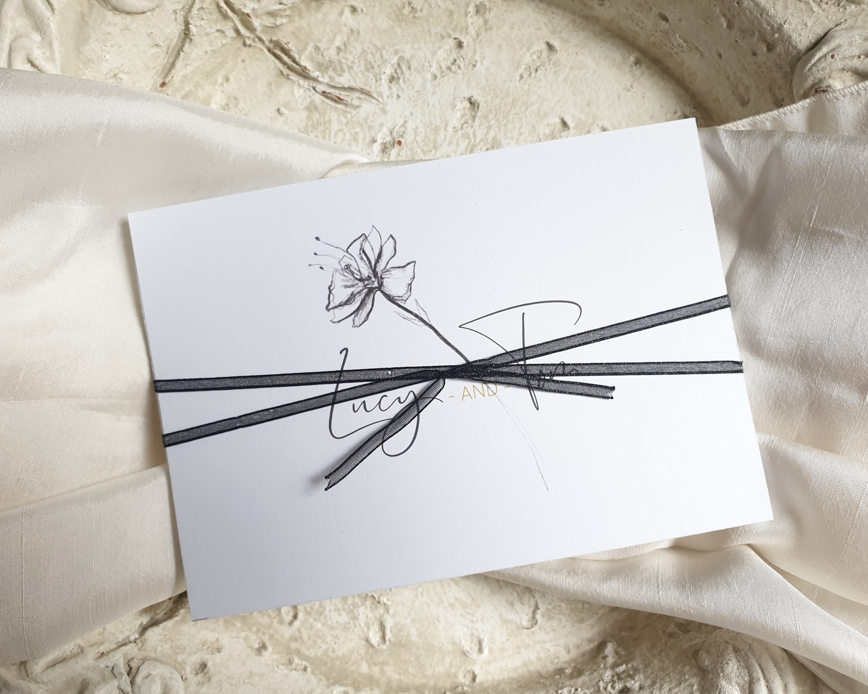 Pencil sketch floral A6 Poppleberry accordion fold all-in-one wedding invitation, folded & wrapped with black ribbon bow.