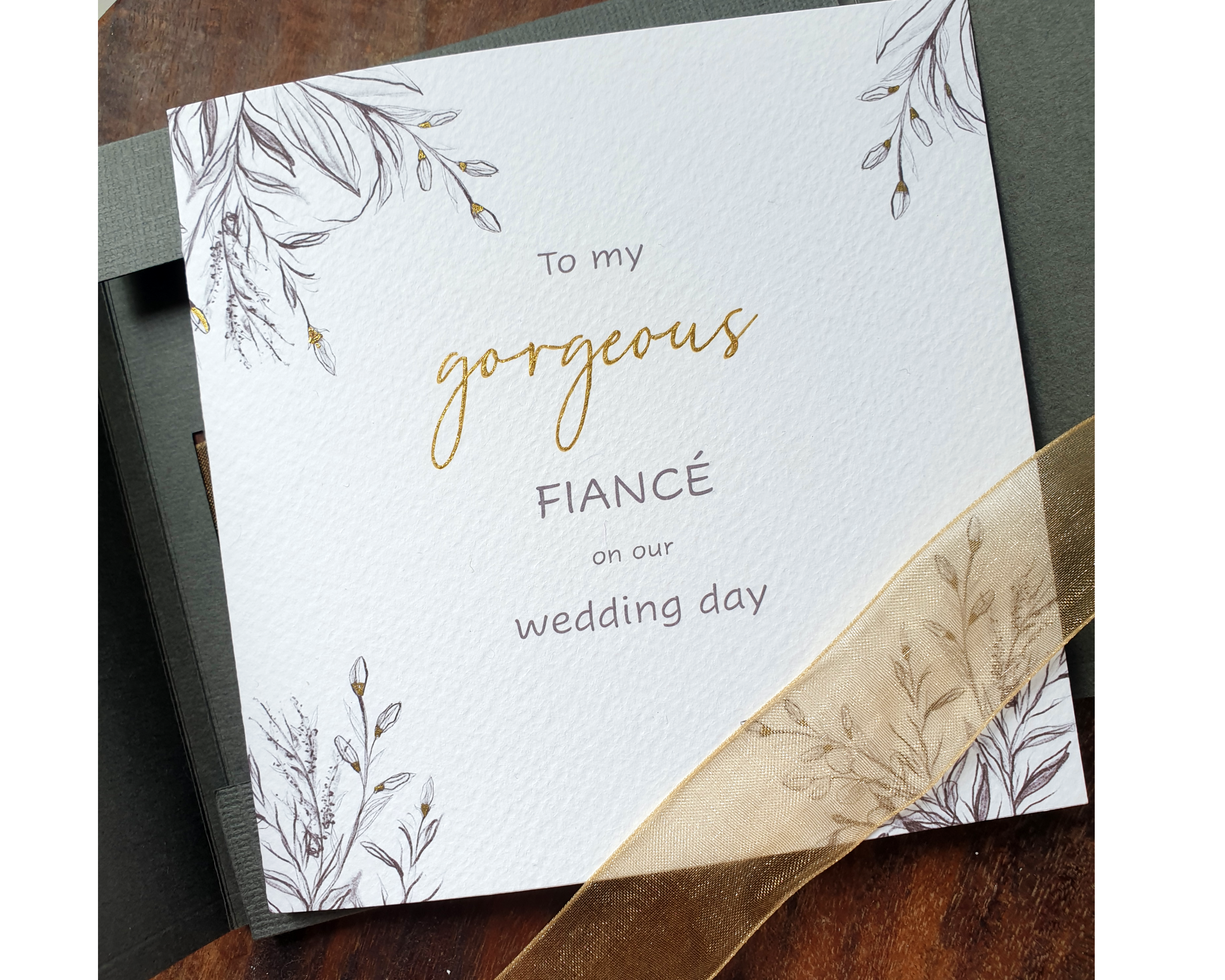 Front of a Poppleberry square luxury charcoal-design wedding day card, laid with golden organza ribbon.