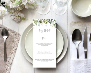 A Poppleberry greenery & eucalyptus wedding menu card, printed with 3-course dinner menu, laid on dining table with cutlery and glasses.