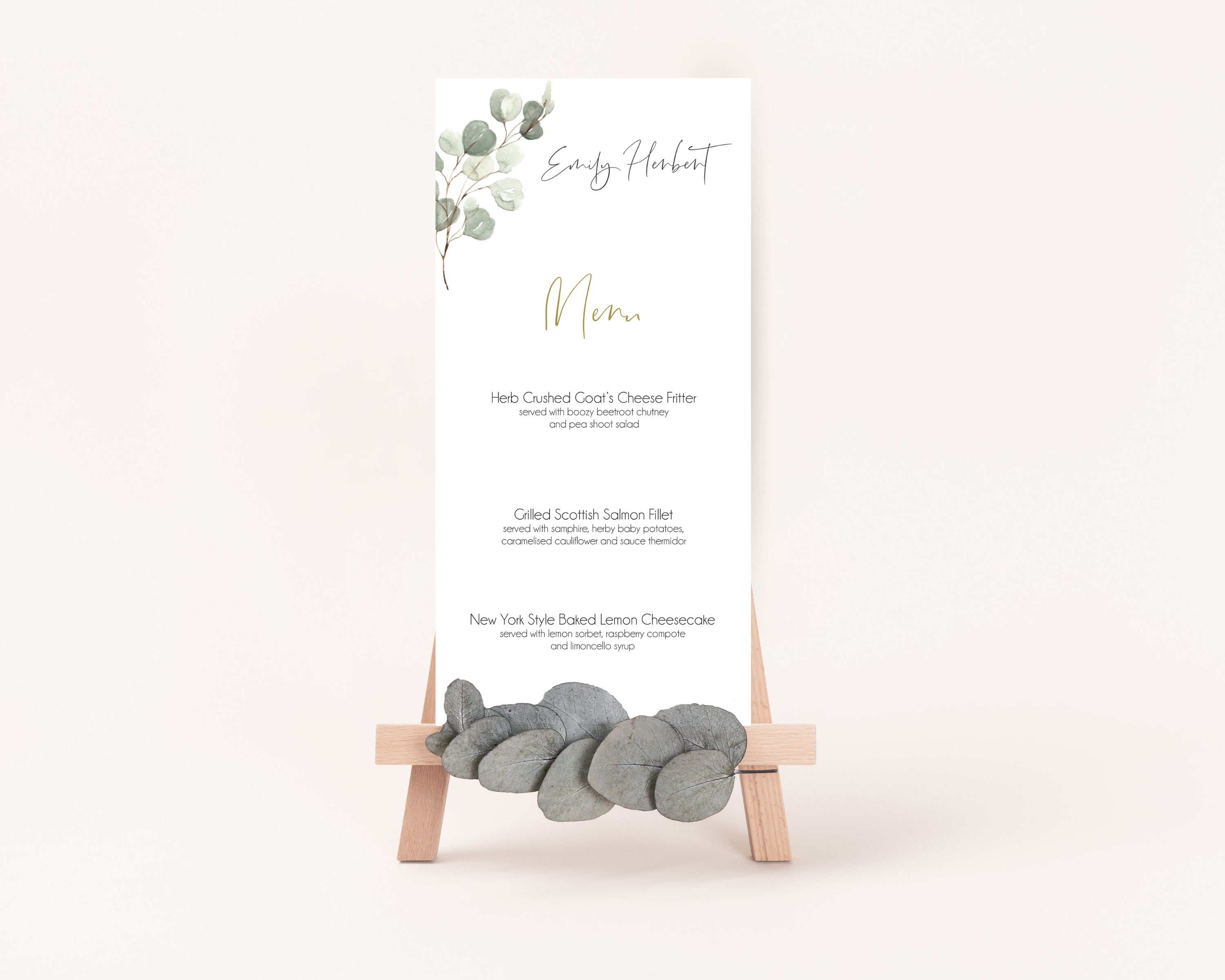 A Poppleberry muted green eucalyptus wedding menu card, printed with 3-course dinner menu, stood up on easel.