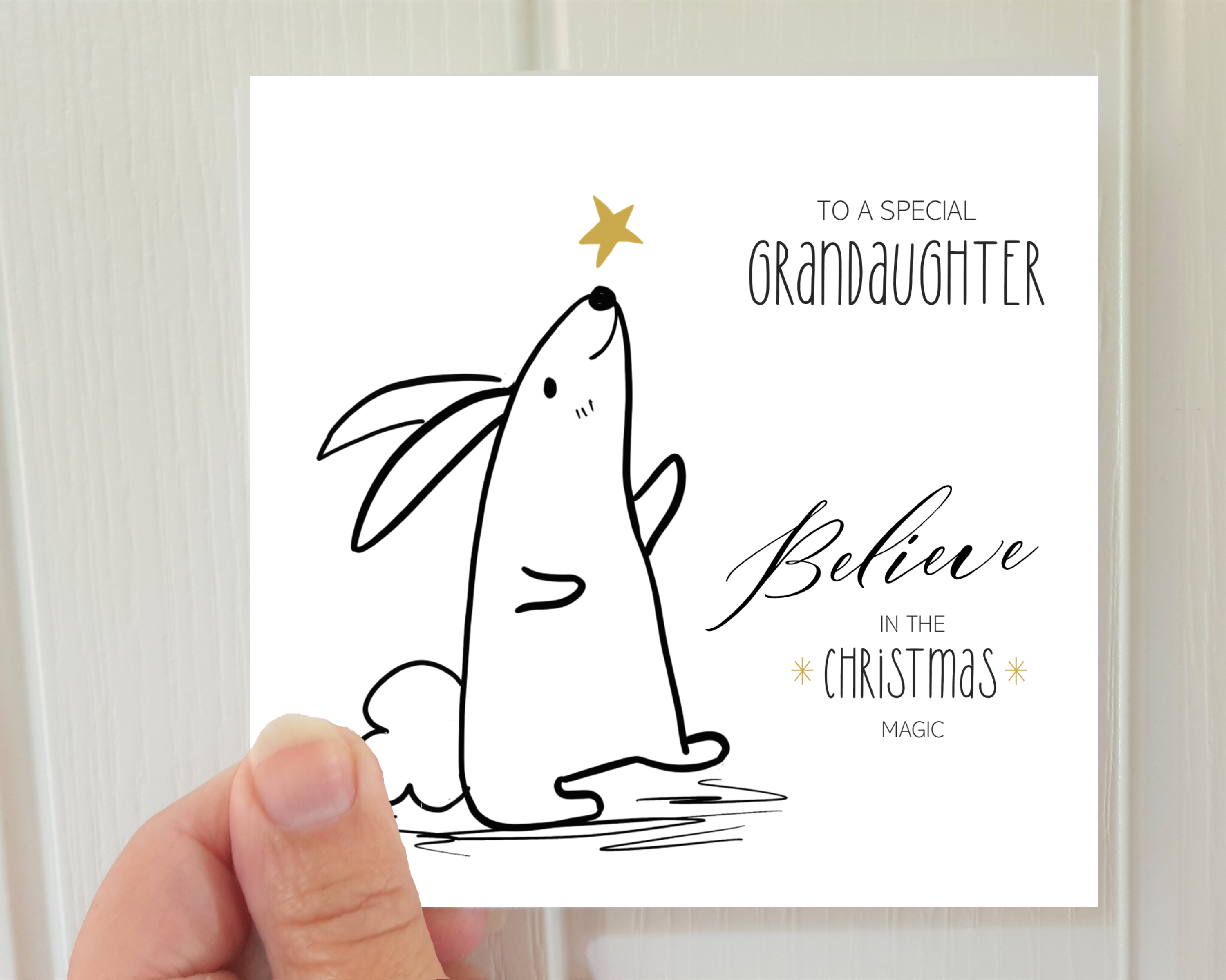 Poppleberry Believe Bunny & Golden Star Illustration 'Grandaughter' family Christmas Card, Held to show size.