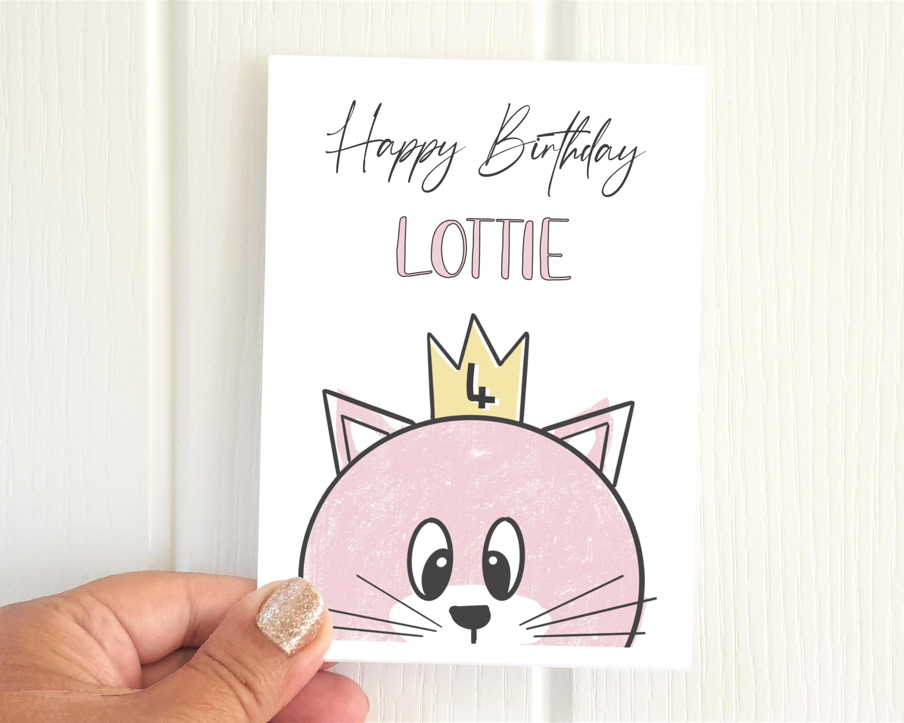 Poppleberry A6 folded birthday card, with a personalised pink cat illustration, on white cardstock, size compared to thumb.