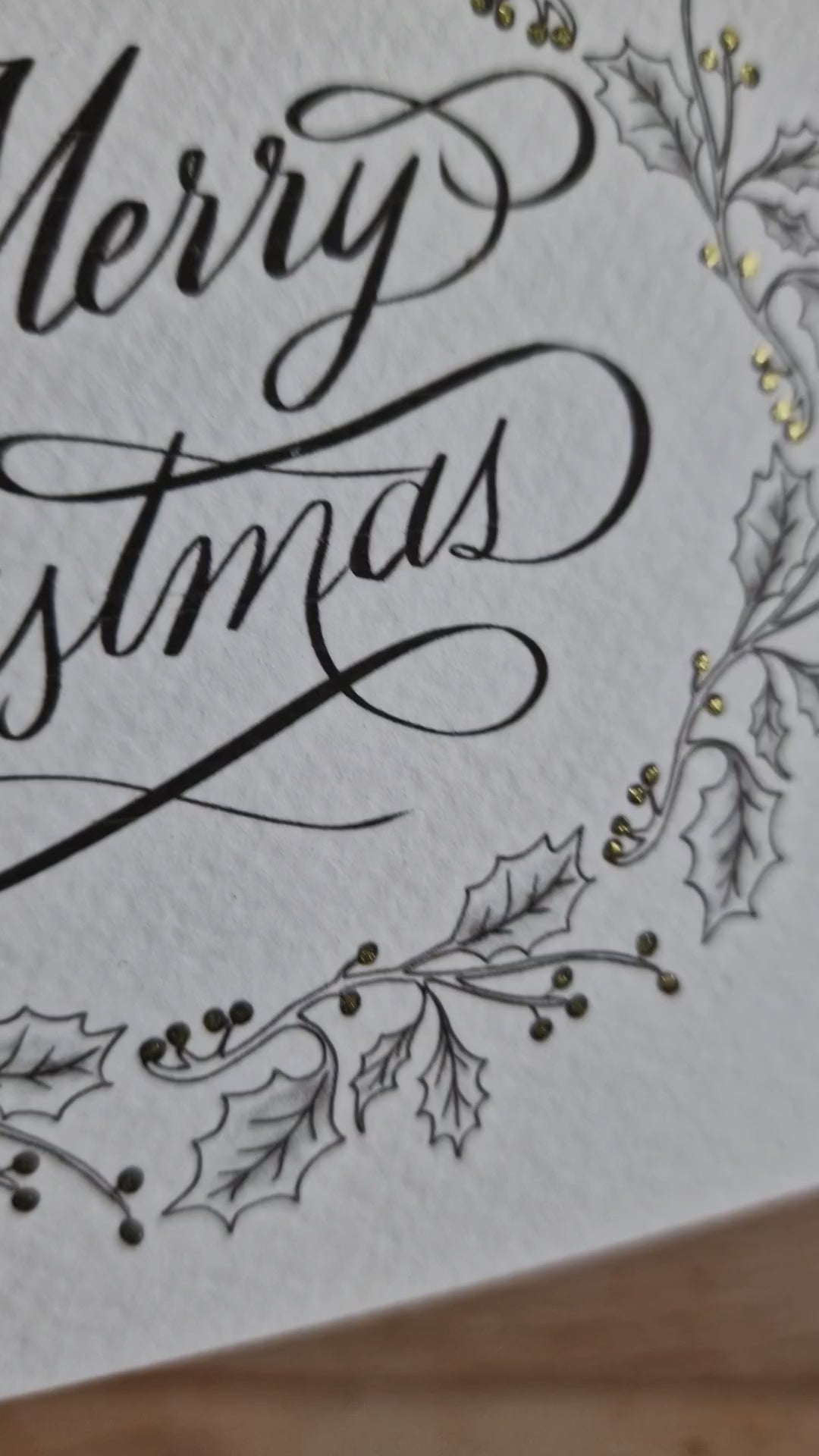 Poppleberry A6 holly wreath Illustration Christmas Card, tilted to show golden glitter pen sparkle.